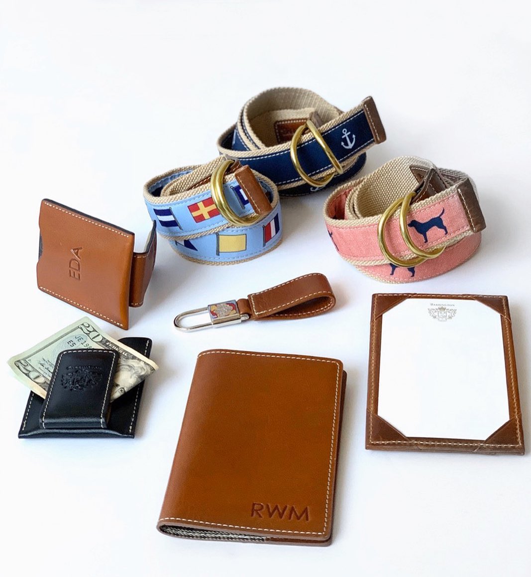 An assortment of leather money clips next to stylish woven belts on a wooden surface.