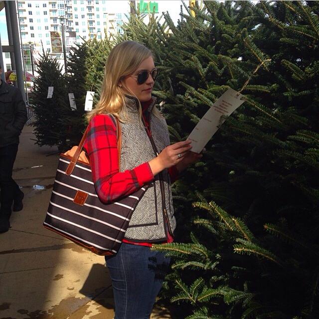Woman selecting a Christmas tree with a stylish monogram purse