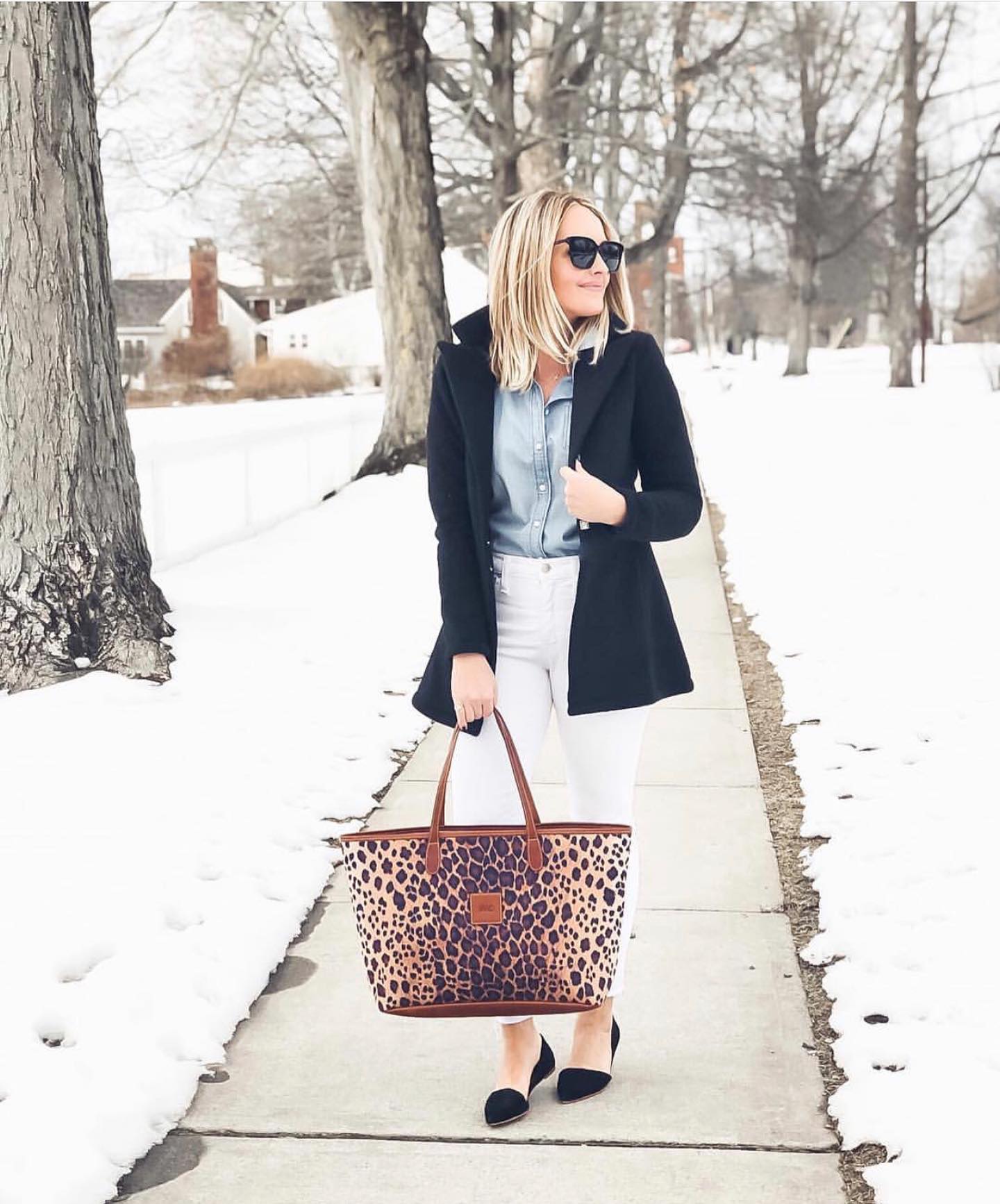 Elegant winter fashion with a tailored black coat, white pants, and a standout leopard print personalized handbag